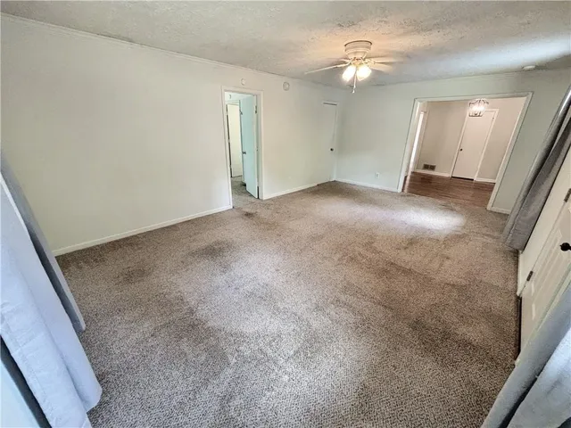 an empty room with a ceiling fan and a rug