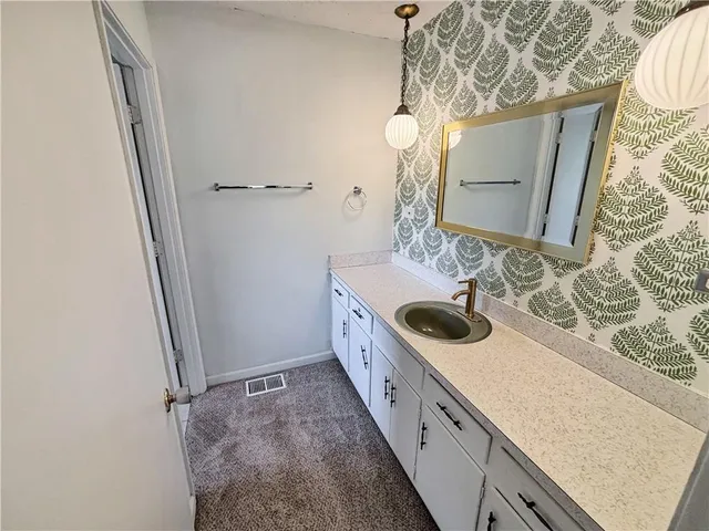 a bathroom with a granite countertop double vanity and a mirror