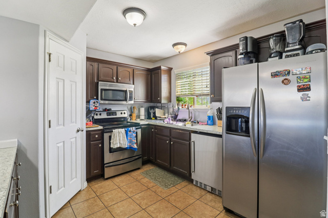 1077 South 1850th Street West Springville, UT 84663 - Photo 9 of 22 Kitchen featuring stainless steel appliances, dark wood finish cabinets, light countertops, and light tile patterned flooring