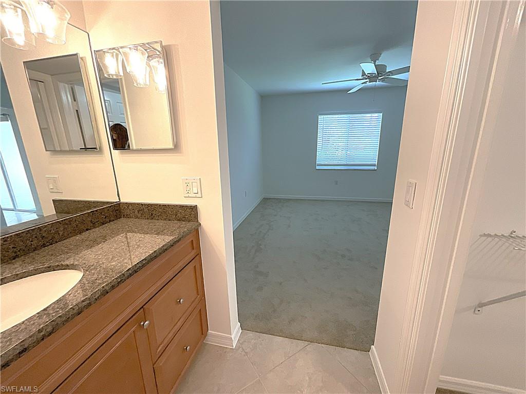 3002 Sandpiper Bay Circle, Unit A103 Naples, FL 34112 - Photo 11 of 25 a bathroom with a granite countertop sink and a mirror