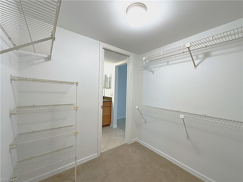 3002 Sandpiper Bay Circle, Unit A103 Naples, FL 34112 - Photo 13 of 25 a view of walk in closet with empty racks