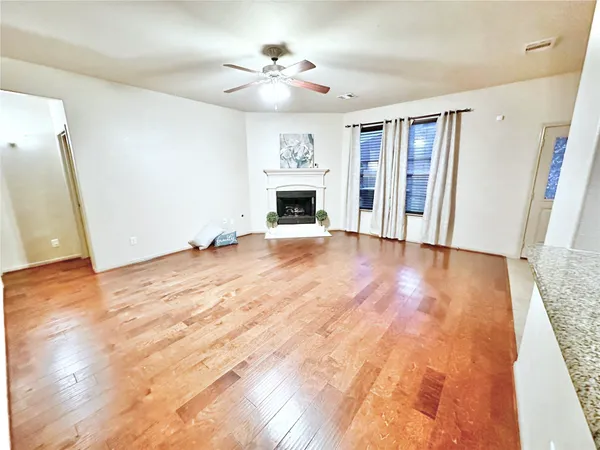 a view of an empty room with wooden floor fireplace and a window