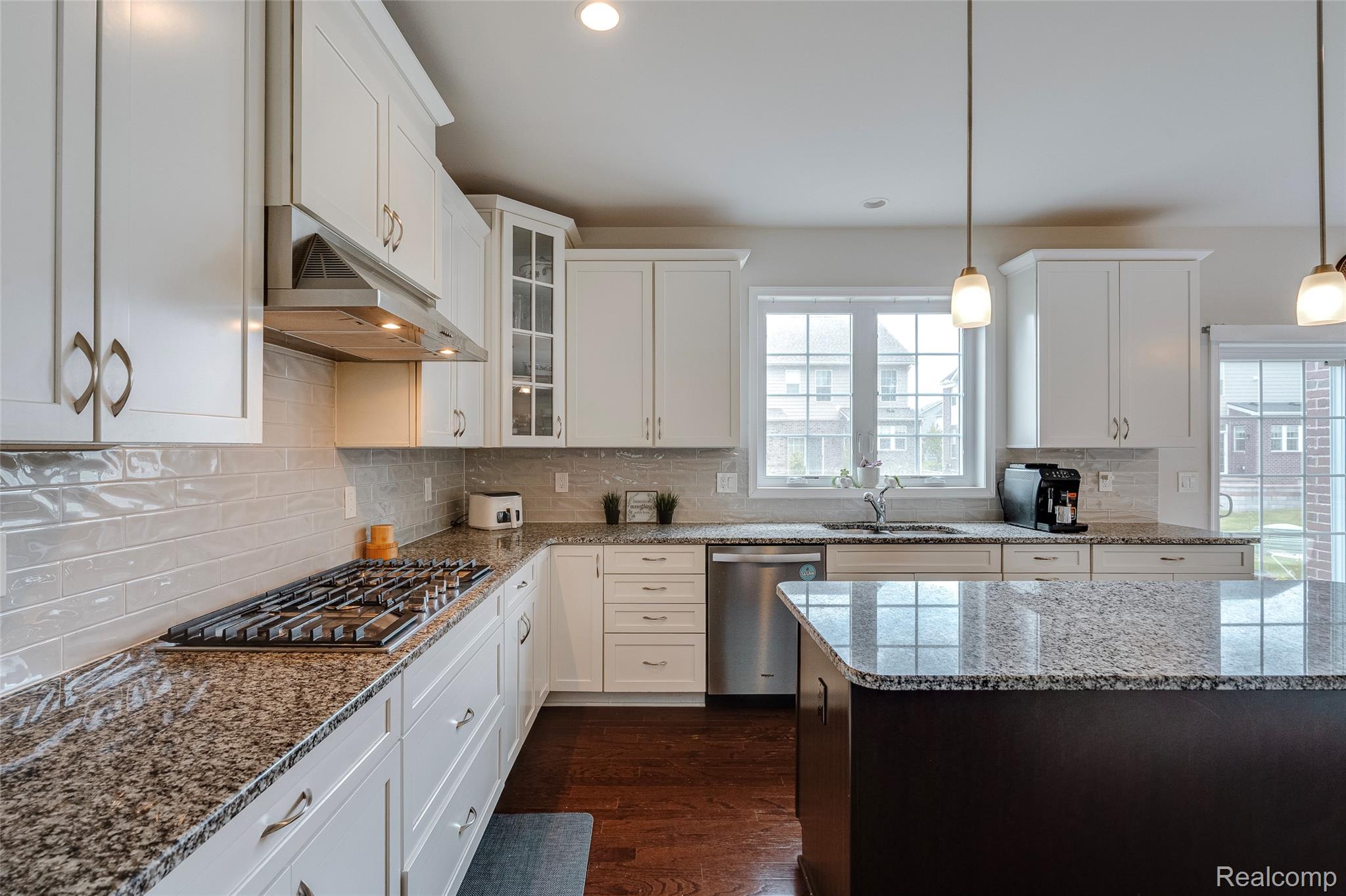 51011 Rockingham Drive Canton, MI 48188 - Photo 12 of 74 Dual tone kitchen with glass fronted cabinets, light stone countertops, dark wood-style floors, stainless steel appliances, and pendant lighting