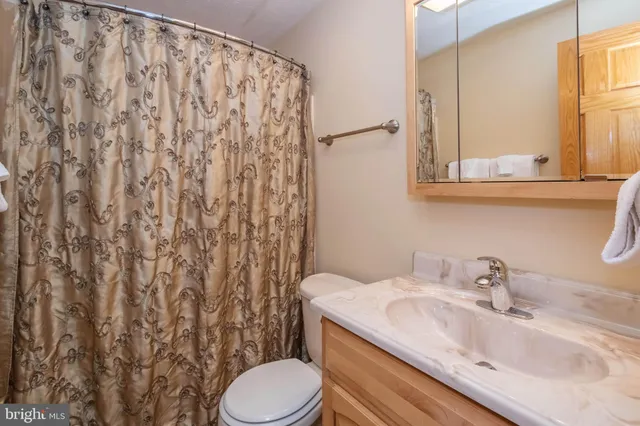 a bathroom with a granite countertop sink and a toilet