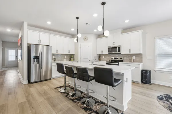 a kitchen with stainless steel appliances kitchen island granite countertop a refrigerator a stove a kitchen island with a dining table and chairs