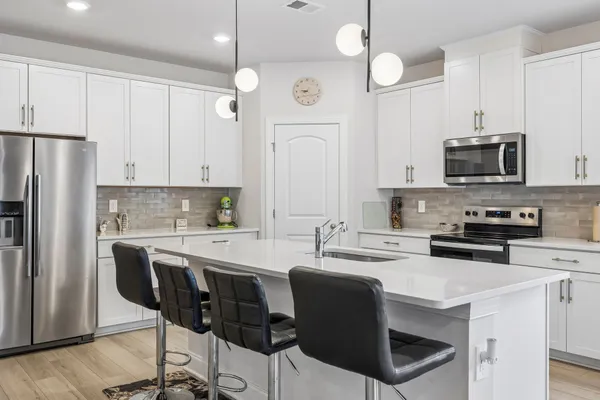 a kitchen with kitchen island white cabinets a refrigerator a oven a stove and a refrigerator with wooden floor