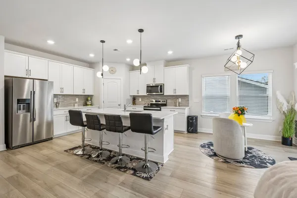 a kitchen with kitchen island granite countertop a refrigerator a stove a oven and a dining table with wooden floor