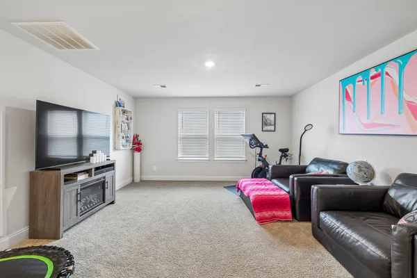 a living room with furniture a flat screen tv and gym equipment