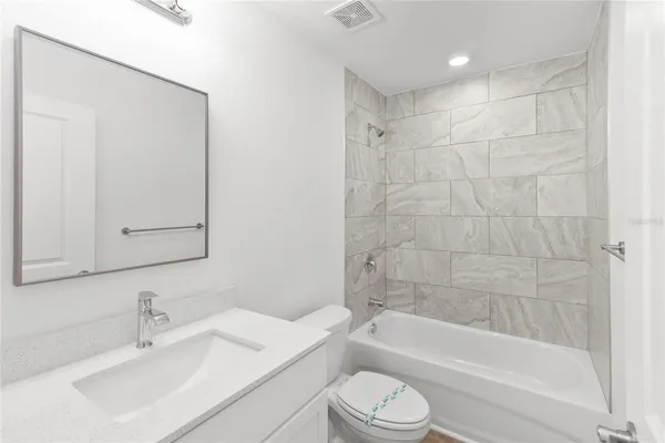 a bathroom with a bathtub shower sink vanity mirror and toilet