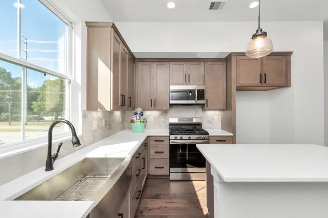 a kitchen with kitchen island a sink appliances cabinets and a large window