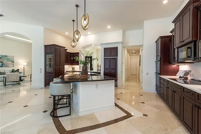 a kitchen with stainless steel appliances kitchen island granite countertop a stove top oven a sink dishwasher a dining table and chairs with wooden floor