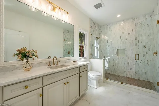 a bathroom with a double vanity sink mirror double shower and a toilet
