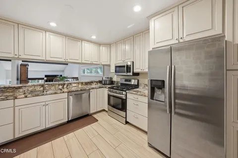 a kitchen with granite countertop a refrigerator sink and cabinets