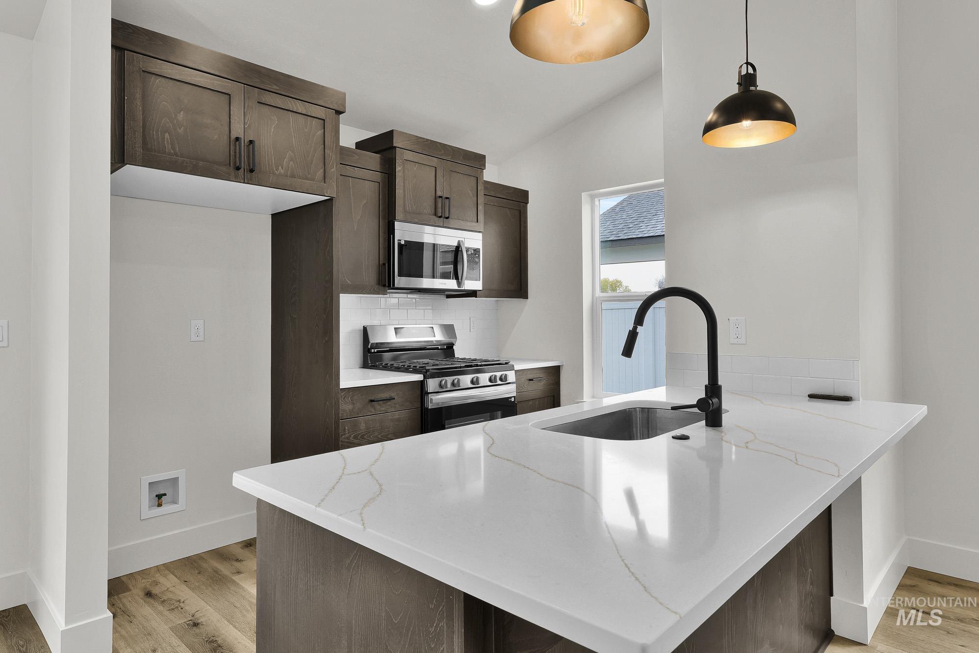 323 North 12th Street Parma, ID 83660 - Photo 10 of 28 Kitchen featuring a peninsula, dark wood finish cabinetry, stainless steel appliances, tasteful backsplash, and lofted ceiling