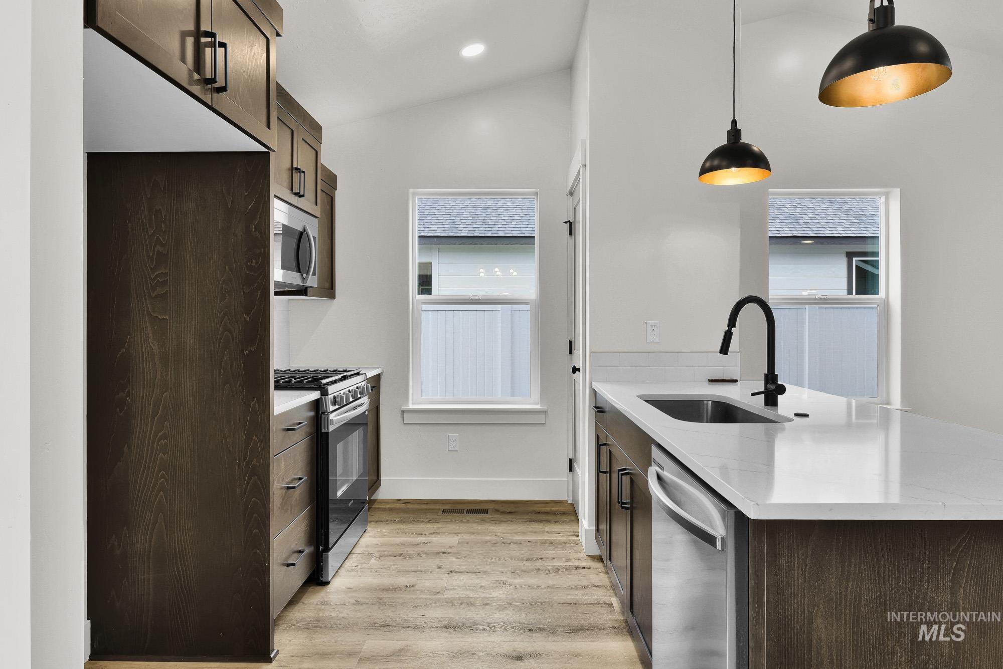 323 North 12th Street Parma, ID 83660 - Photo 11 of 28 Kitchen with a peninsula, light stone countertops, stainless steel appliances, dark wood finish cabinets, and lofted ceiling