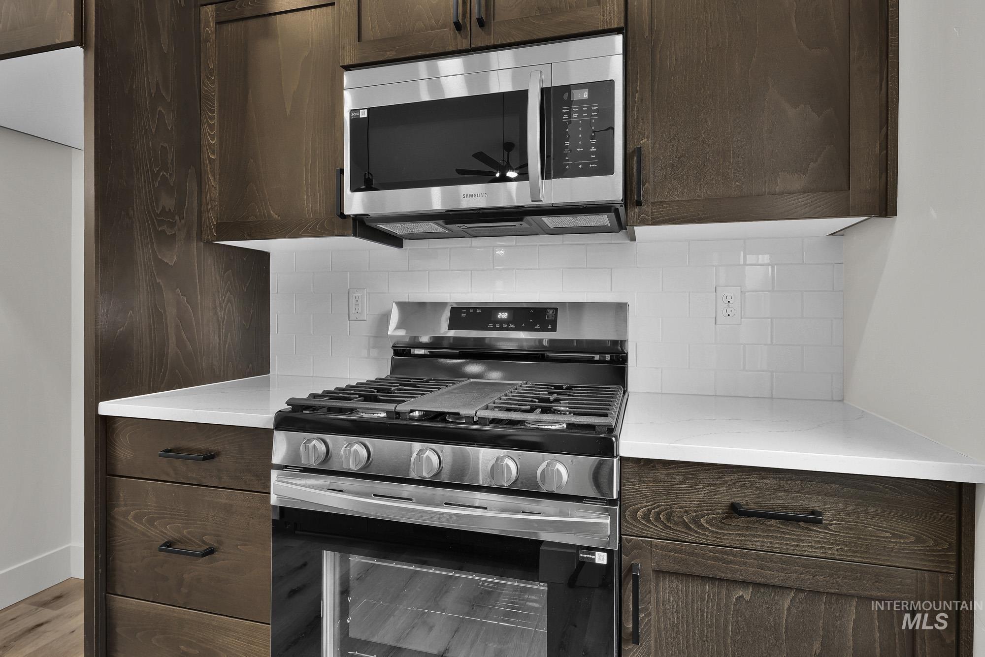323 North 12th Street Parma, ID 83660 - Photo 12 of 28 Kitchen with stainless steel appliances, dark wood finish cabinetry, decorative backsplash, and light stone countertops