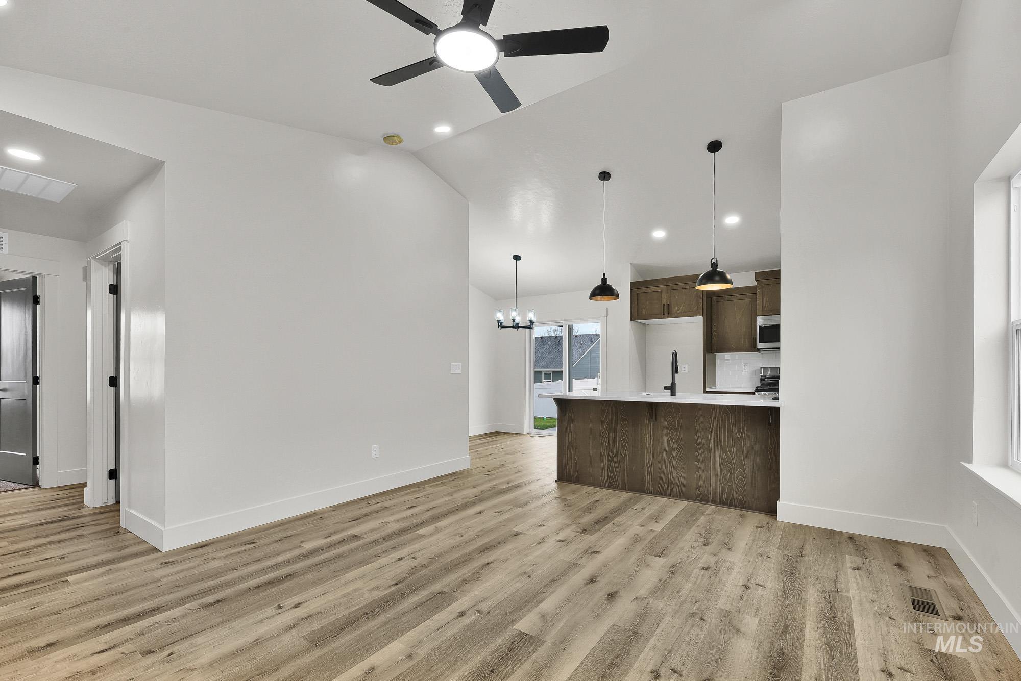 323 North 12th Street Parma, ID 83660 - Photo 4 of 28 Unfurnished living room with lofted ceiling, suspended lighting, a ceiling fan, and light wood-style floors