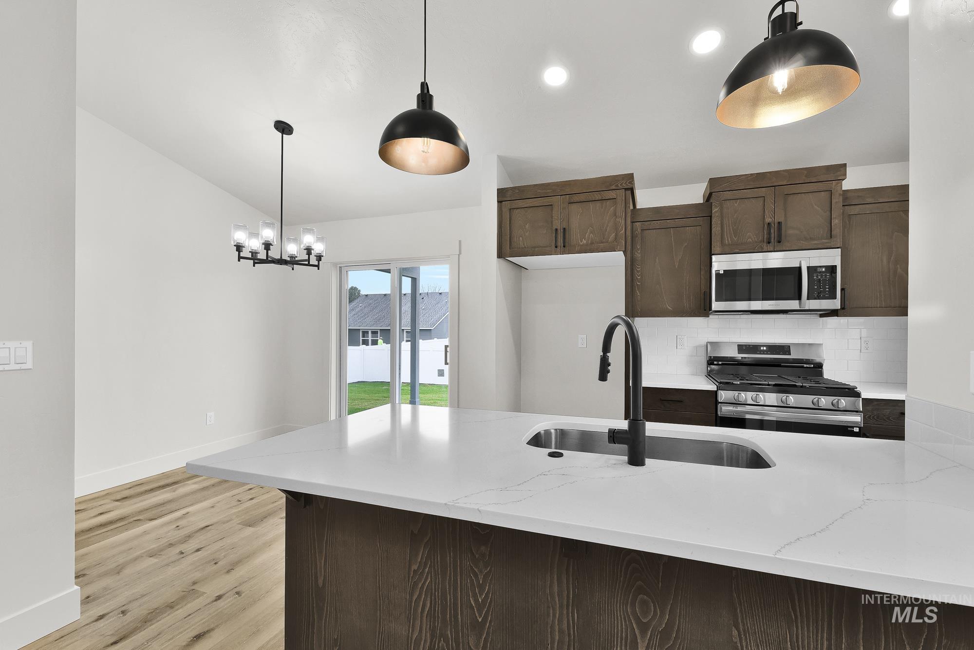 323 North 12th Street Parma, ID 83660 - Photo 7 of 28 Kitchen with dark wood finish cabinets, stainless steel appliances, light stone countertops, tasteful backsplash, and a peninsula