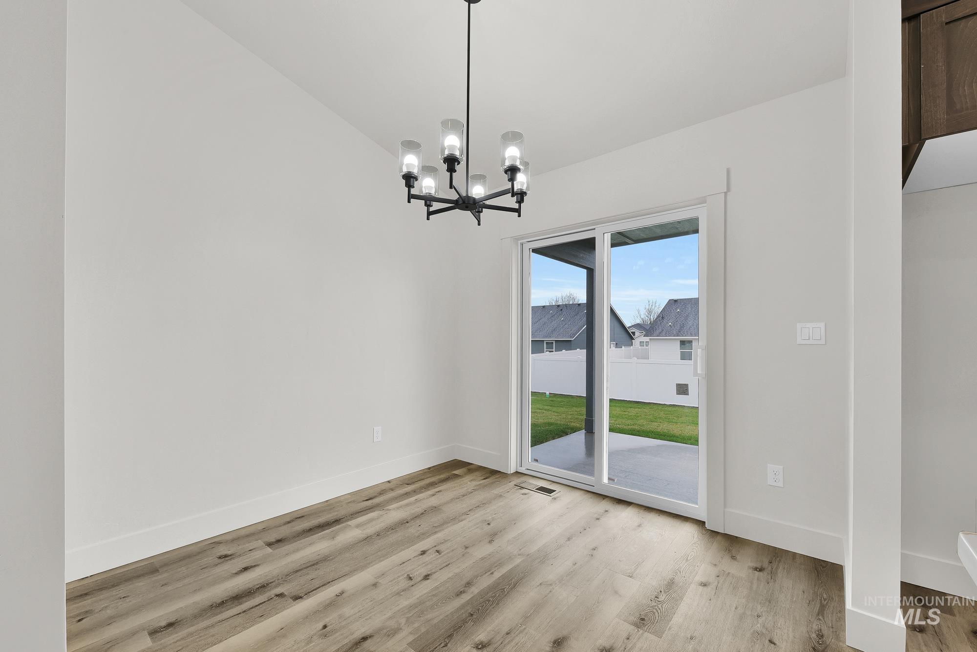 323 North 12th Street Parma, ID 83660 - Photo 8 of 28 Unfurnished dining area with a chandelier, light wood-style floors, and vaulted ceiling
