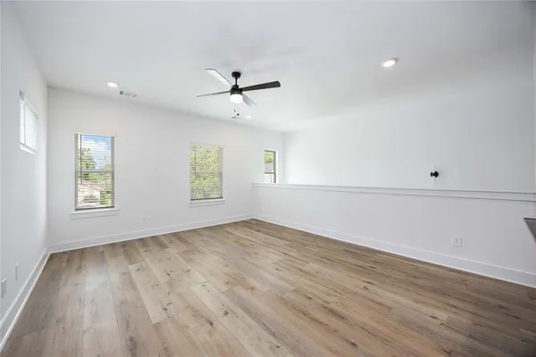 a view of empty room with wooden floor and fan