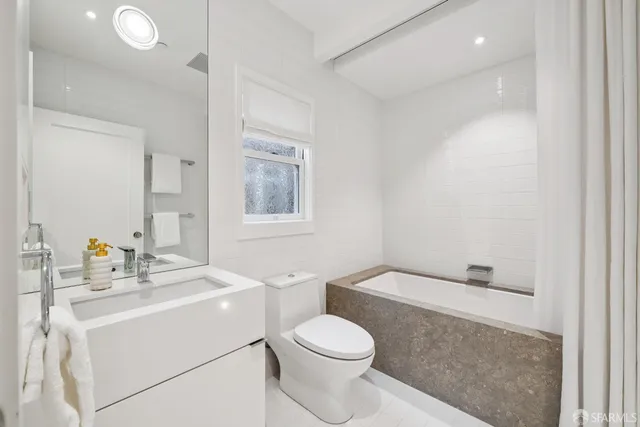 a bathroom with a tub sink and mirror