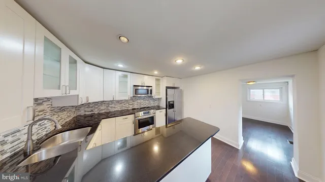 a large kitchen with stainless steel appliances granite countertop a granite counter tops and a wooden floors