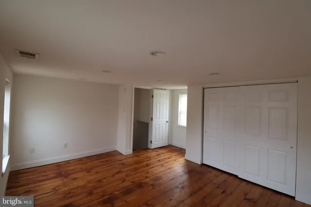 a view of an empty room with wooden floor and closet