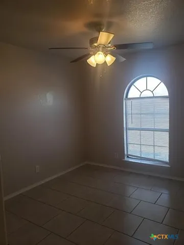 en empty room with windows and chandelier fan