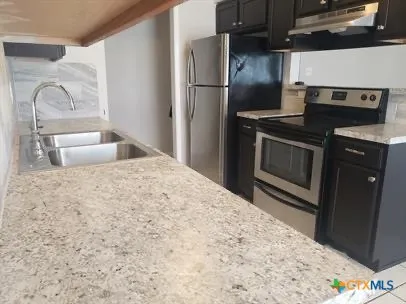 a kitchen with granite countertop a refrigerator stove and sink