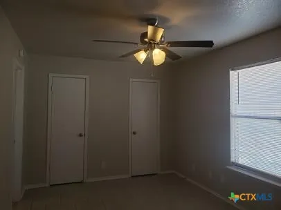 an empty room with windows and fan