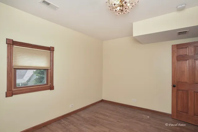 an empty room with a hallway and wooden floor