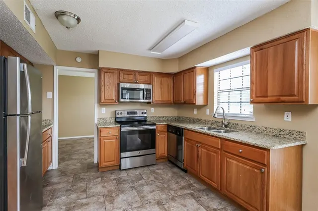 a kitchen with stainless steel appliances granite countertop a stove top oven a refrigerator a sink and dishwasher