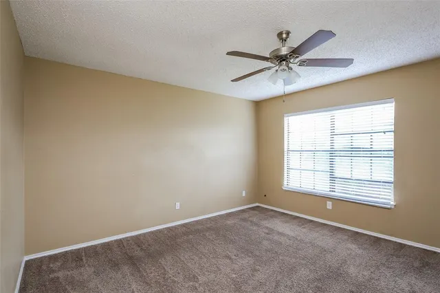 an empty room with a window and a fan