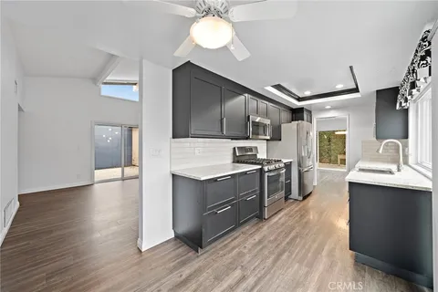 a kitchen with stainless steel appliances kitchen island hardwood floor sink stove and wooden cabinets