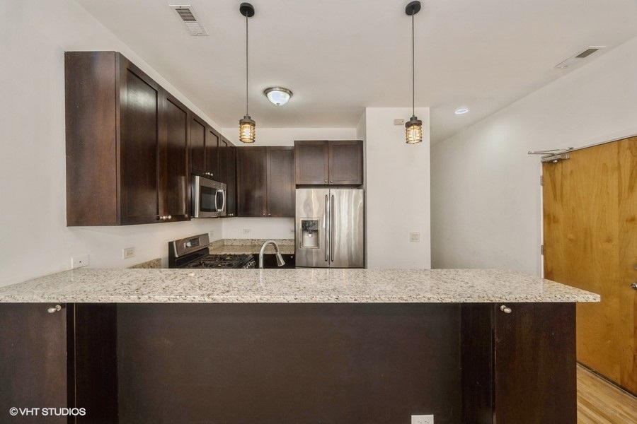 2444 West Madison Street, Unit 3 Chicago, IL 60612 - Photo 4 of 14 a kitchen with stainless steel appliances granite countertop a sink a refrigerator and a granite counter tops
