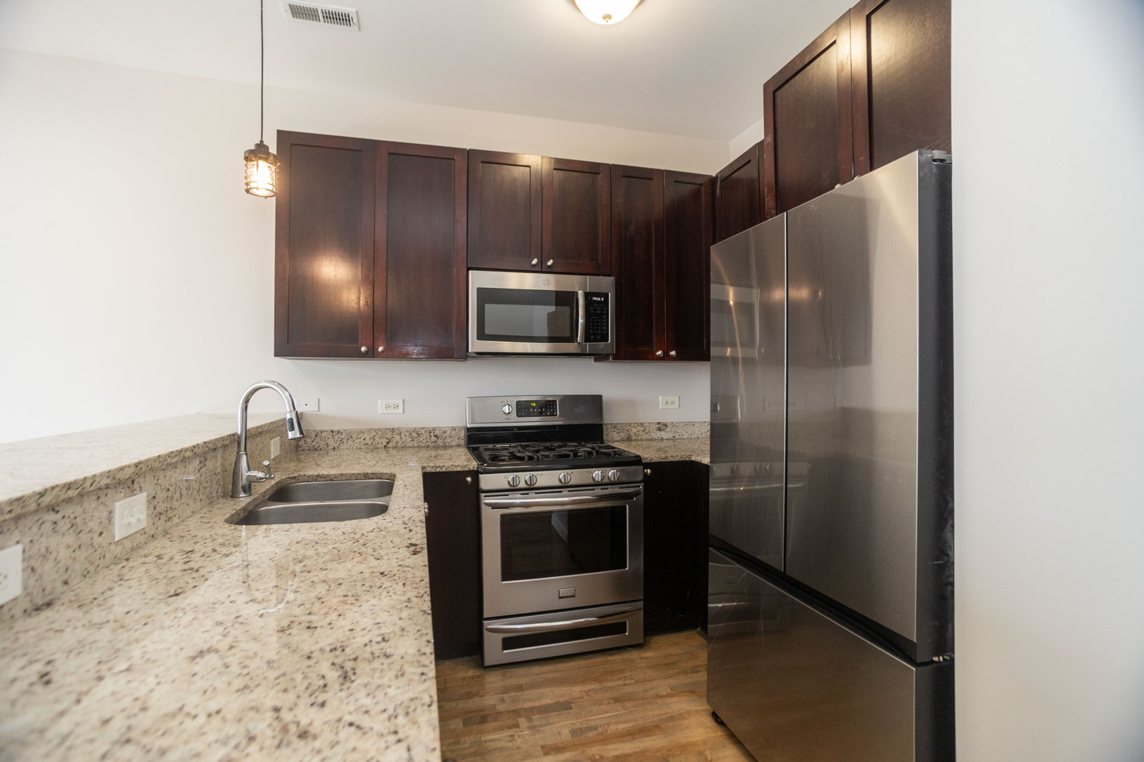 2444 West Madison Street, Unit 3 Chicago, IL 60612 - Photo 7 of 14 a kitchen with granite countertop a refrigerator and a stove top oven