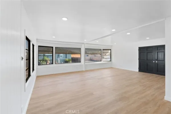 a view of an empty room with a window and refrigerator