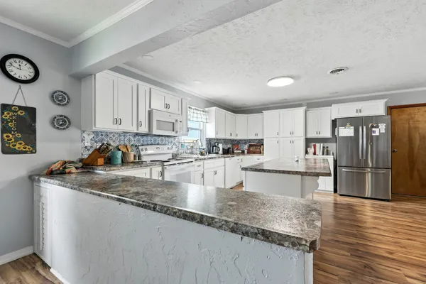 a kitchen with stainless steel appliances granite countertop a sink refrigerator and cabinets