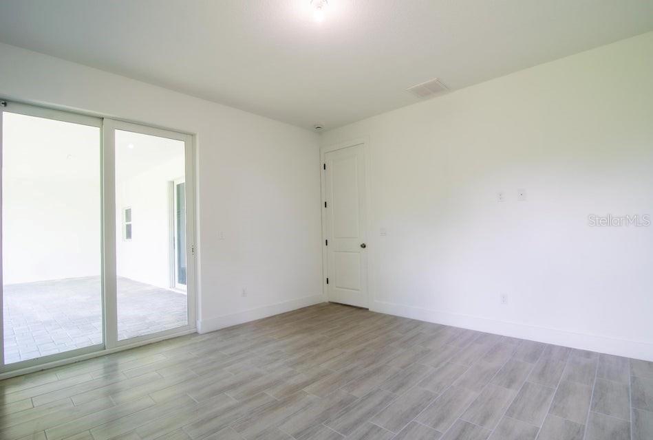 10654 Washington Road Port Charlotte, FL 33981 - Photo 17 of 35 an empty room with wooden floor and sliding door