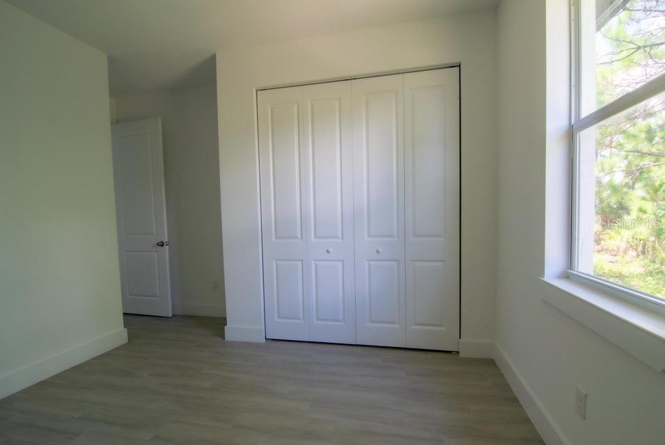 10654 Washington Road Port Charlotte, FL 33981 - Photo 22 of 35 an empty room with wooden floor and windows