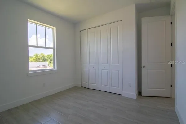 an empty room with wooden floor closet and windows