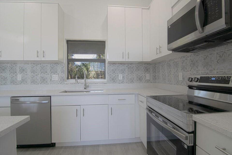 10654 Washington Road Port Charlotte, FL 33981 - Photo 6 of 35 a kitchen with white cabinets appliances and a sink