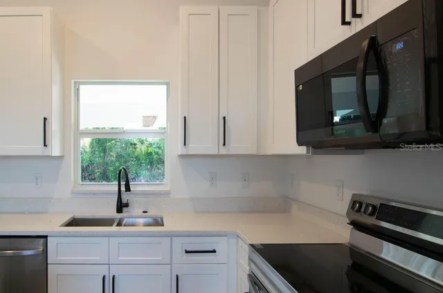 a kitchen with a sink a microwave and cabinets