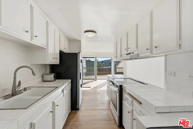a kitchen with a stove a refrigerator and a sink with wooden floor