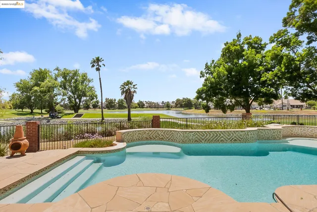 a view of a swimming pool with a patio and a lake view