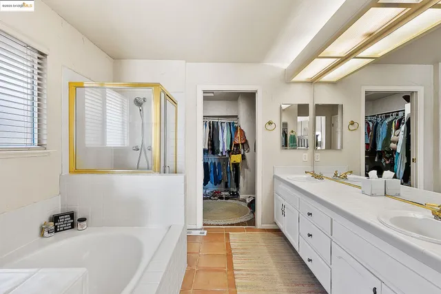 a en suite spacious bathroom with a double vanity sink a large mirror and a bathtub