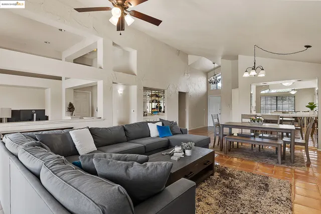a living room with furniture kitchen view and a chandelier