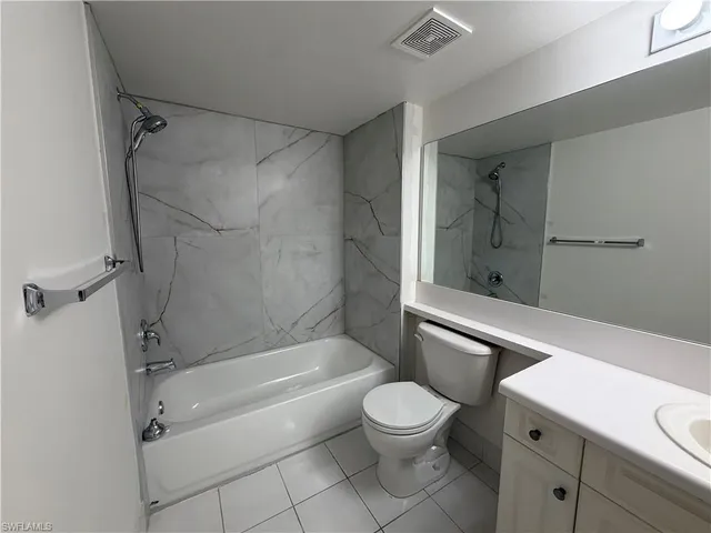 a bathroom with a granite countertop bathtub shower sink vanity and toilet