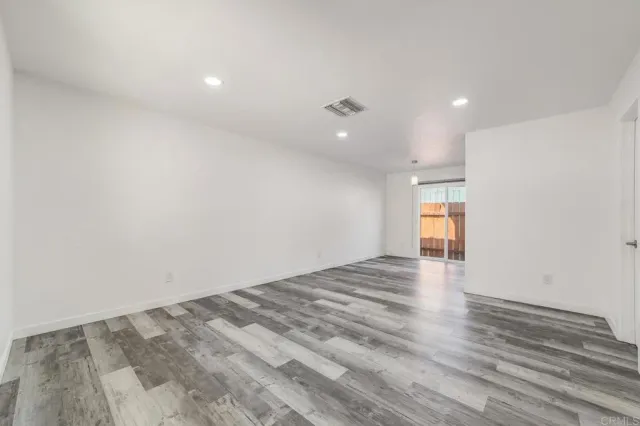 a view of empty room with wooden floor and windows
