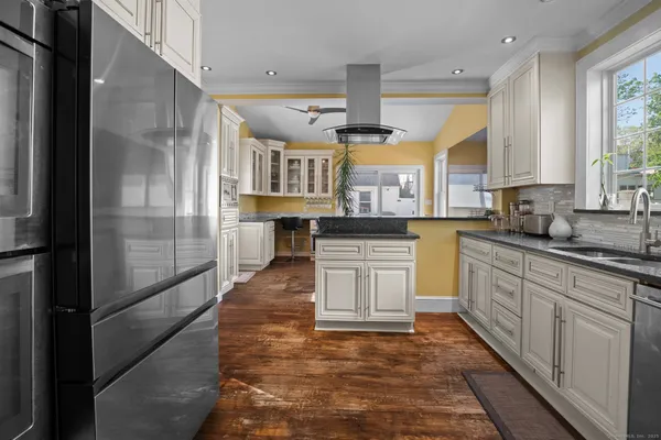 a large kitchen with stainless steel appliances kitchen island granite countertop a refrigerator a stove and a sink